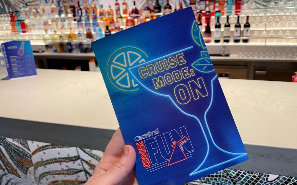 Blue and orange Cruise Mode On box with lemon and straw icon, in front of bar shelves.