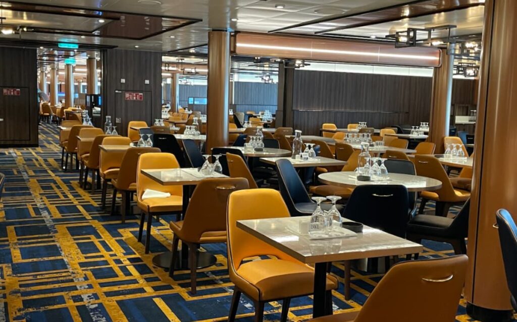 Spacious dining area with numerous yellow chairs and tables, modern interior design, and scenic views.