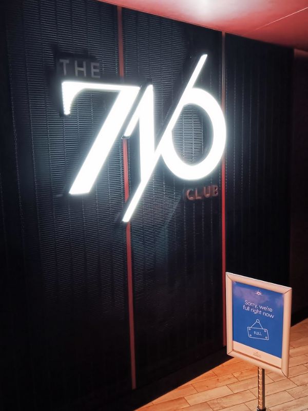 The illuminated entrance sign of 'The 710 Club' on P&O's Iona, with a signboard reading 'Sorry, we're full right now,' indicating a bustling scene within the exclusive venue, reflecting the club's popularity among guests.
