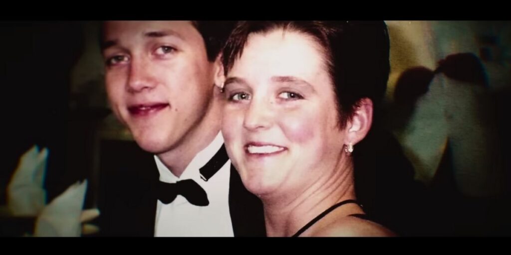 Photo of Amy Bradley smiling next to a young man in formal wear, taken from a Netflix documentary about her disappearance. Amy is wearing a black spaghetti-strap top and small hoop earrings.
