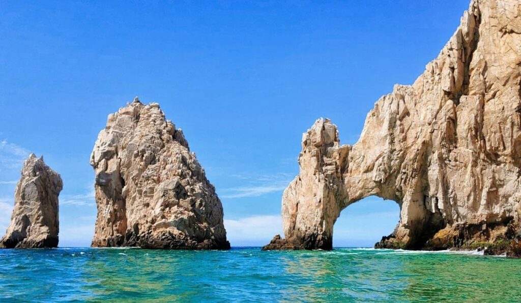 El Arco rock formation in Cabo San Lucas, Mexico, rising from turquoise water under a clear blue sky.