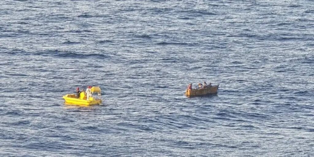 Royal Caribbean's yellow rescue boat approaches a small, crowded boat drifting in choppy open water off the coast of Cuba.
