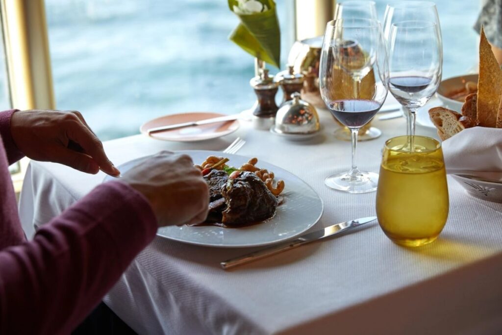 Guest enjoying an elegant dinner by the window on a Holland America cruise ship.