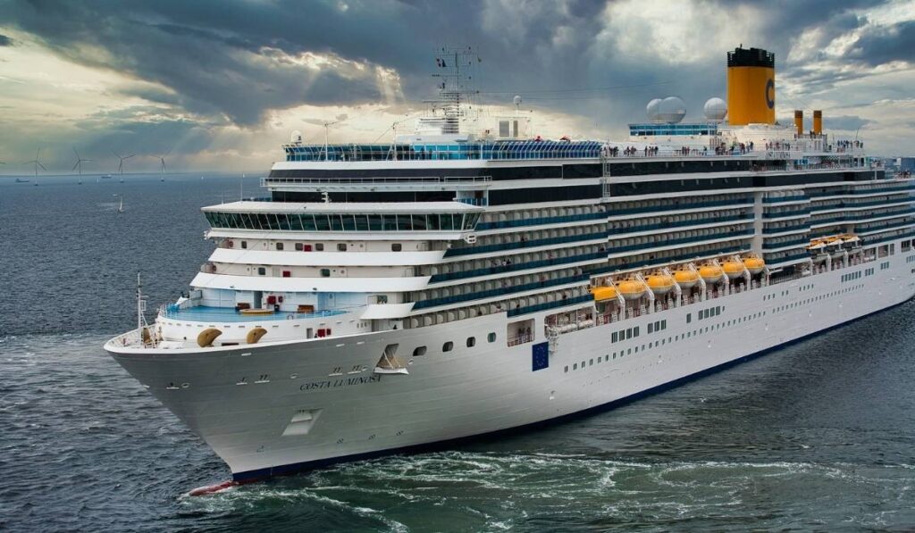 Costa Luminosa cruise ship sailing on open water beneath dramatic storm clouds.