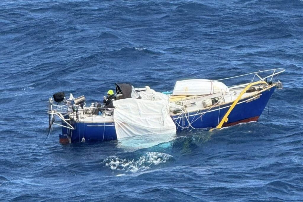 Injured sailor wearing a green hat aboard the disabled sailboat April Alice during the Silver Whisper rescue.