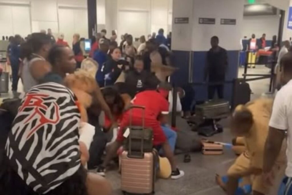 Several people appear to be fighting in a busy cruise terminal while other passengers and suitcases crowd the area.