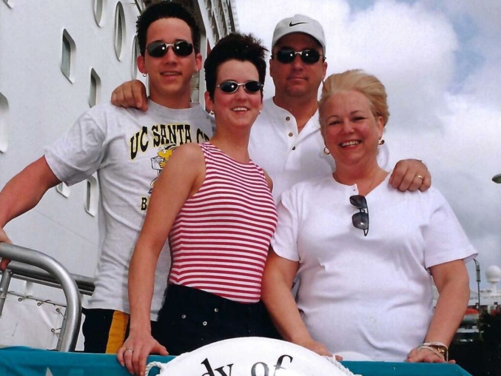 Amy Bradley poses with her family on pier next to Rhapsody of the Seas cruise ship. 