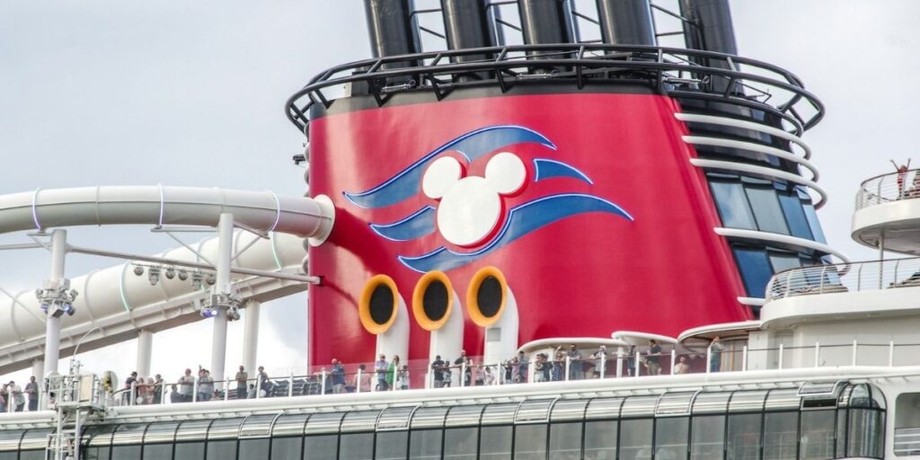 Disney Wish funnel with Mickey logo on the top deck, with waterslides and guests visible.