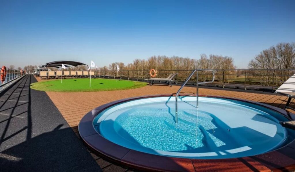 Top deck of Riviera Travel’s MS George Eliot with a small round plunge pool, lounge chairs, mini golf area, and open river views under a clear blue sky.
