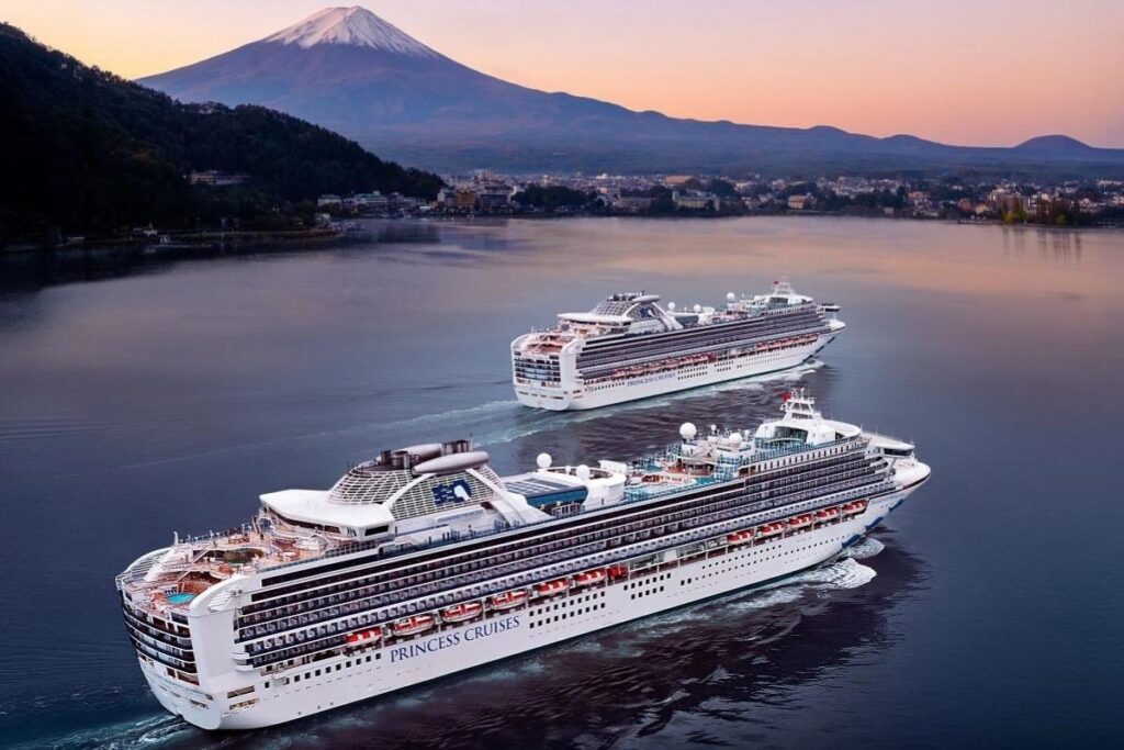 Two Princess Cruises ships sailing near Mount Fuji in Japan at sunset.