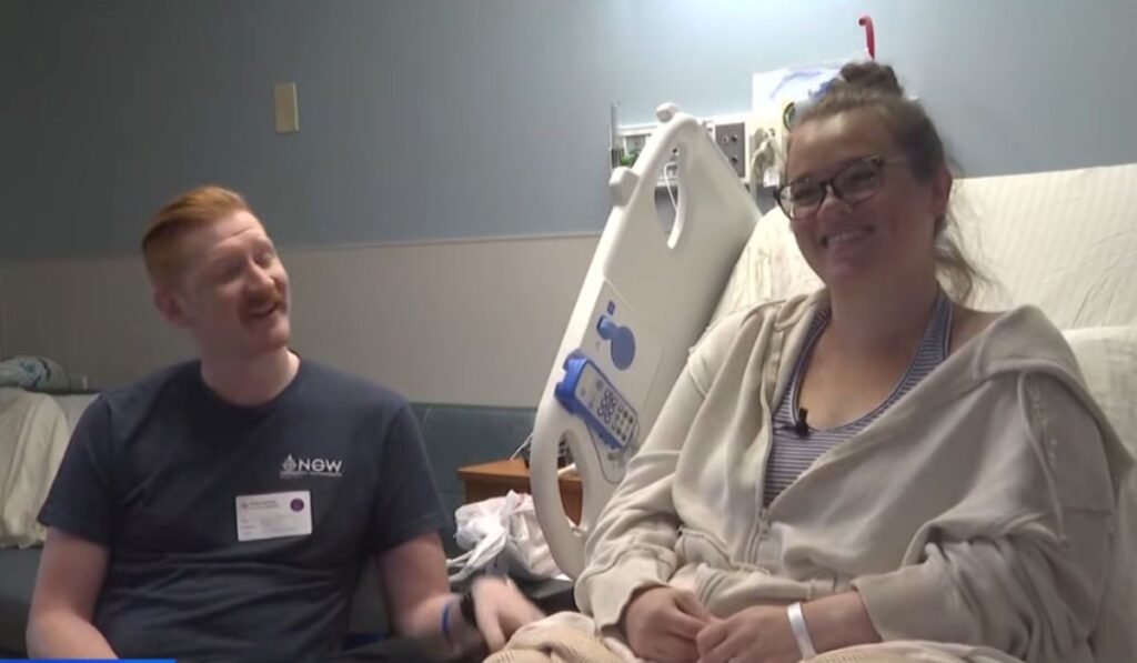 New parents sitting beside a hospital bed and smiling during an interview after the unexpected birth of their son.