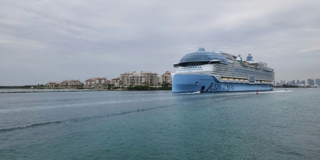 Icon of the Seas sailing near Miami with Biscayne Bay waterfront condos in the background.
