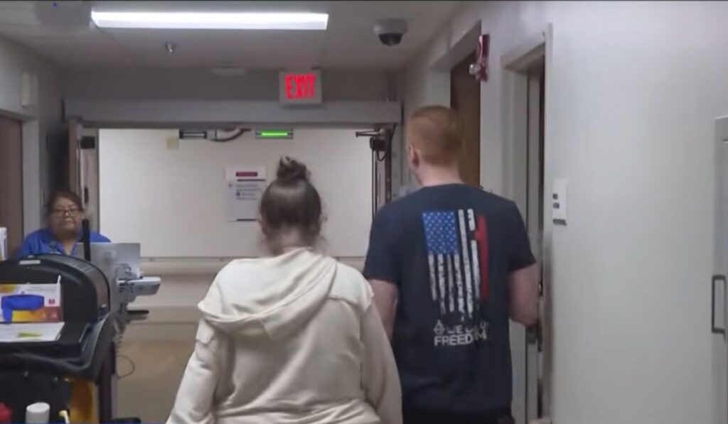 A couple walking through a hospital corridor toward a maternity ward after arriving in Tampa for a cruise.