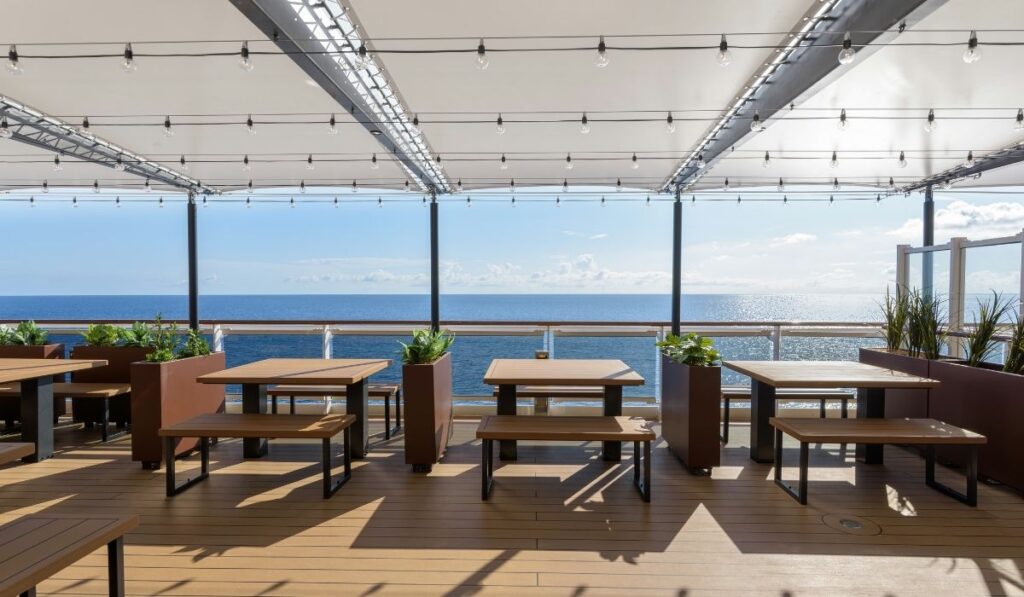 Shaded outdoor seating area on MSC Seashore for new venue Red Cactus BBQ & Ribs with picnic tables and ocean views behind the dining venues