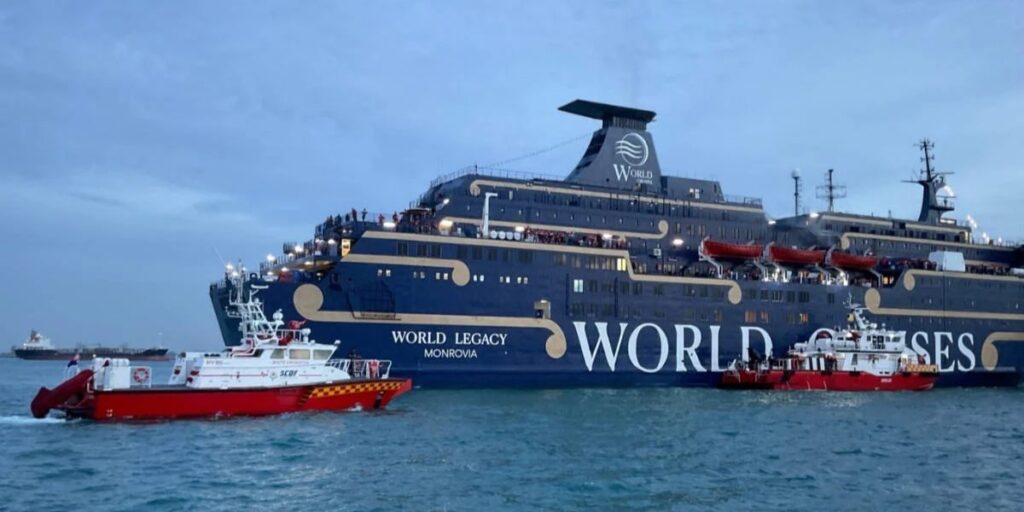 World Legacy cruise ship at sea with two red emergency response boats in the foreground.