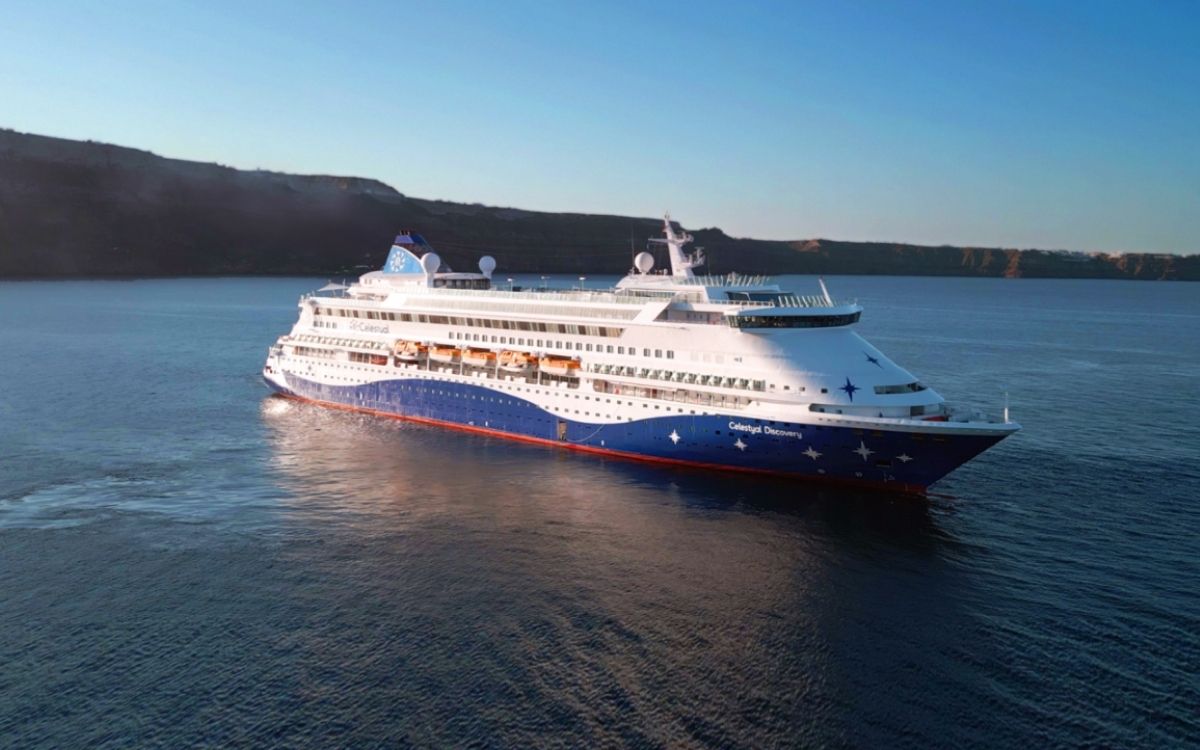 Celestyal Discovery sailing at sea near a rocky coastline.