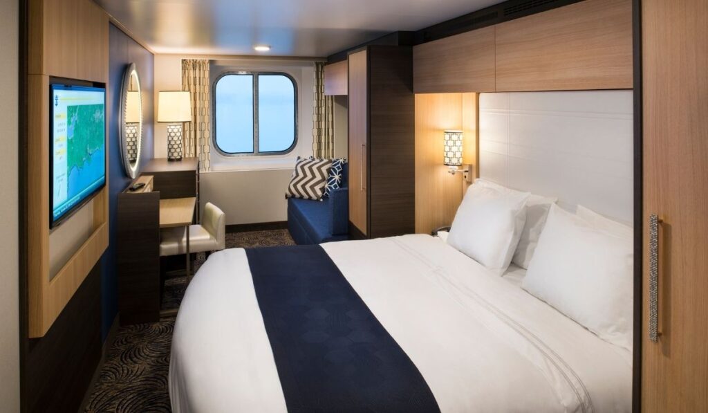 Royal Caribbean oceanview stateroom with a bed, sofa, desk, and large window.