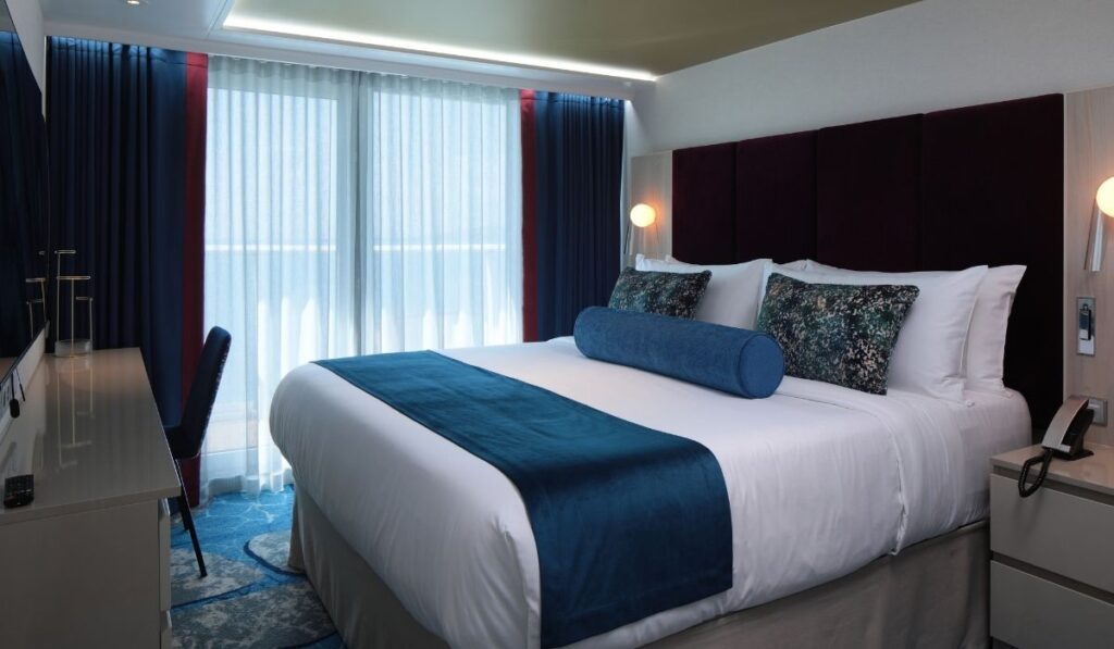 Royal Caribbean balcony stateroom with a bed, desk, and sliding glass doors to a private veranda.