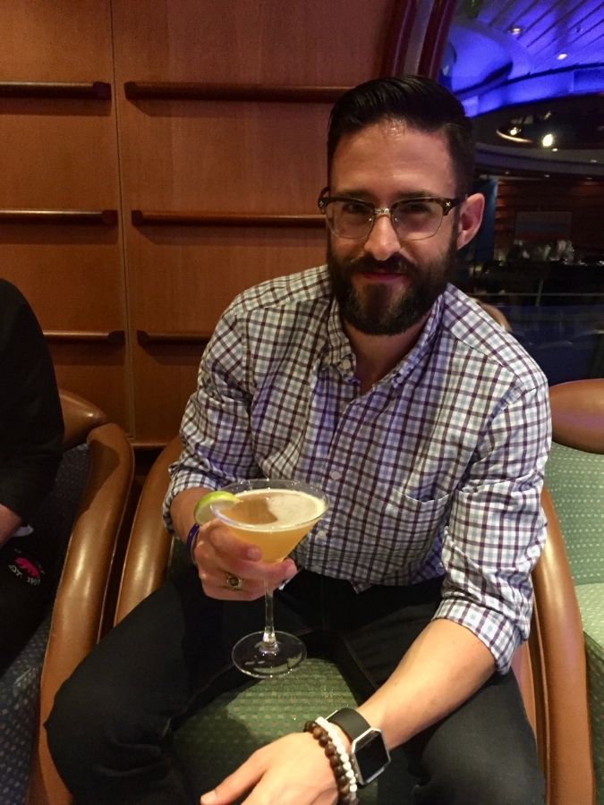Man holding a cocktail in a cruise ship lounge.