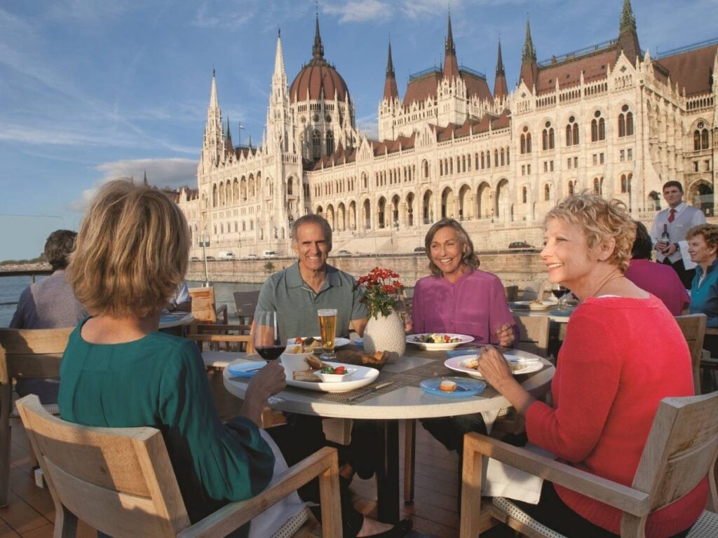 Guests dine outdoors on a Viking river cruise ship along the Danube River as it sails past the Hungarian Parliament Building in Budapest.