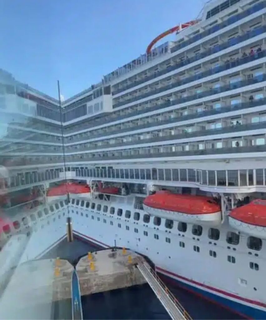 Carnival Breeze docked beside the pier in Cozumel, with the ship’s starboard side and rows of balcony cabins visible above the dock.