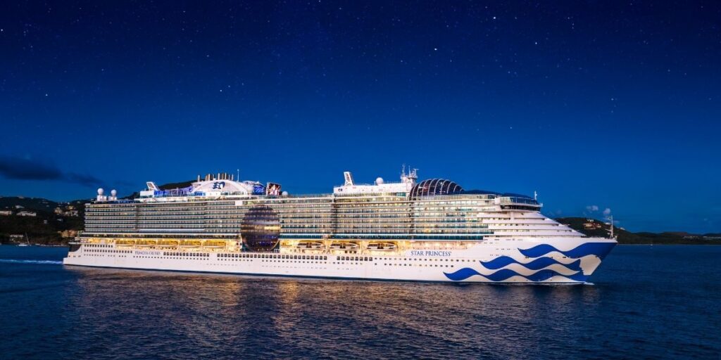 Princess Cruises’ Star Princess sailing at night, illuminated under a clear dark-blue sky.