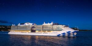 Princess Cruises’ Star Princess sailing at night, illuminated under a clear dark-blue sky.