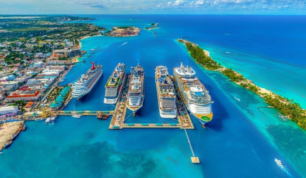 Five cruise ships docked at Nassau Cruise Port with turquoise water surrounding the harbor.