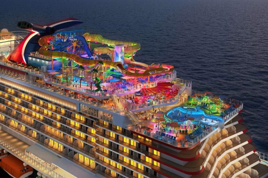 Carnival Tropicale Sunsation Point illuminated at night with waterslides, pools, and outdoor family entertainment.
