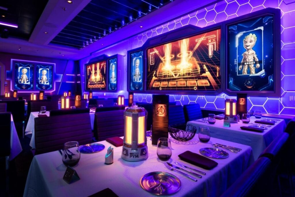 Worlds of Marvel restaurant aboard Disney Cruise Line, featuring futuristic purple lighting, interactive screens displaying Groot, and Marvel-themed dining tables.