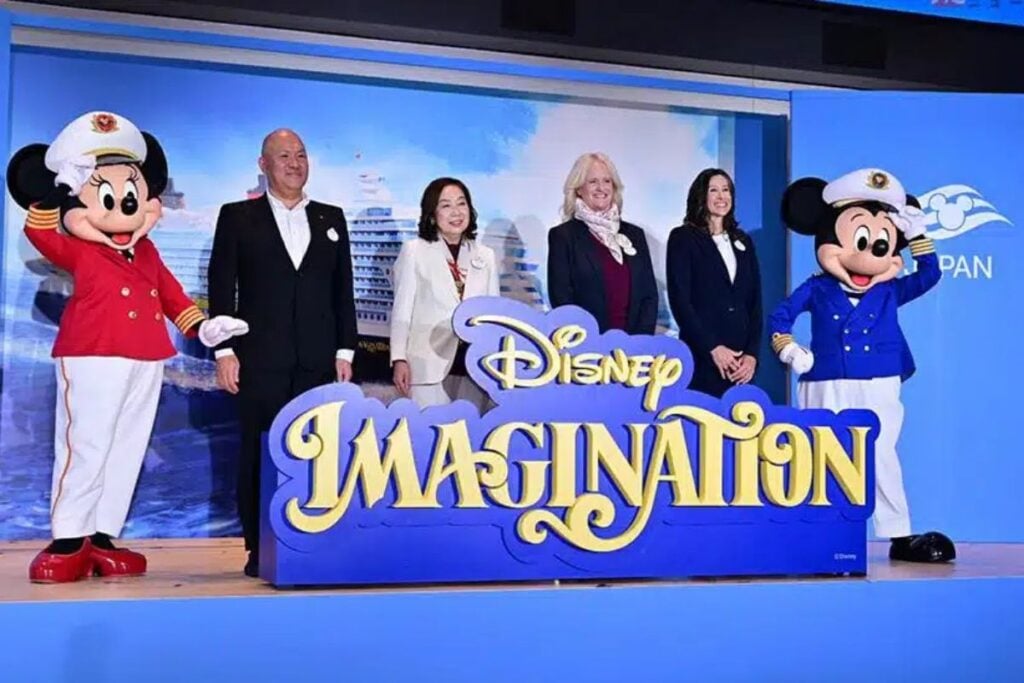 Mickey and Minnie Mouse in captain uniforms pose alongside four executives at the Disney Imagination cruise ship unveiling ceremony in Japan.