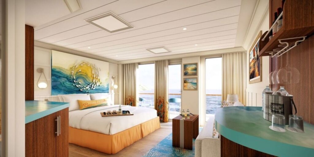 Bright ocean-view cabin aboard the Margaritaville at Sea Beachcomber cruise ship, featuring a king bed with colorful artwork, balcony doors, and tropical-inspired decor.