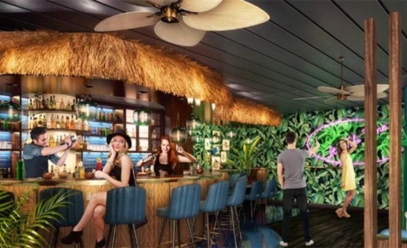 A tropical-themed bar with a thatched roof and lush green decor creates a relaxed island vibe. A bartender is shaking a cocktail while a woman in a black hat sits at the bar, smiling. In the background, a couple interacts near a neon-lit, plant-covered wall, enhancing the vibrant and social atmosphere.