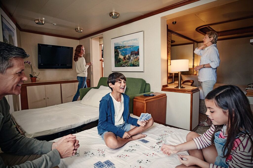 Family playing cards together in a spacious Princess Cruises suite with parents and grandparents nearby.