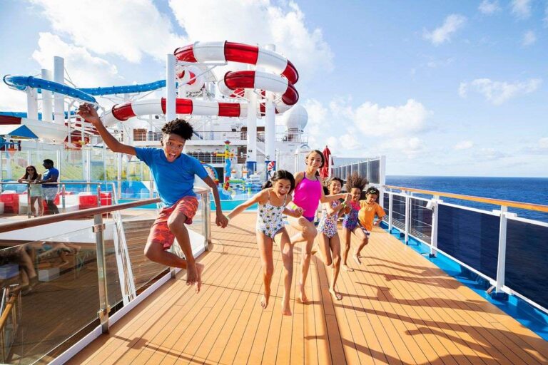 Joyful children running towards the camera on the deck of Carnival WaterWorks, with a colorful waterslide in the background, capturing the excitement and family-friendly fun on a sunny day at sea.