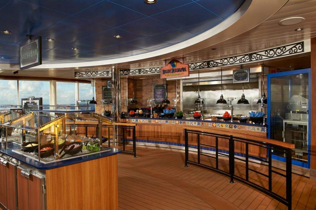 The BlueIguana Cantina on Carnival Celebration offers a tantalizing display of fresh ingredients at the salsa bar, with a clean, inviting design featuring warm wood tones and vibrant blue accents, ready to serve up delicious Mexican fare to cruise guests.