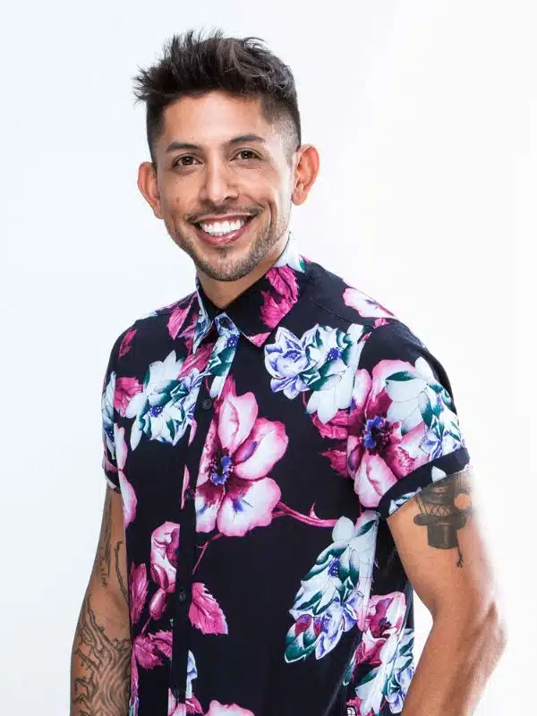 Chris “Donkey” Salazar smiling in a portrait photo, wearing a floral shirt against a light background