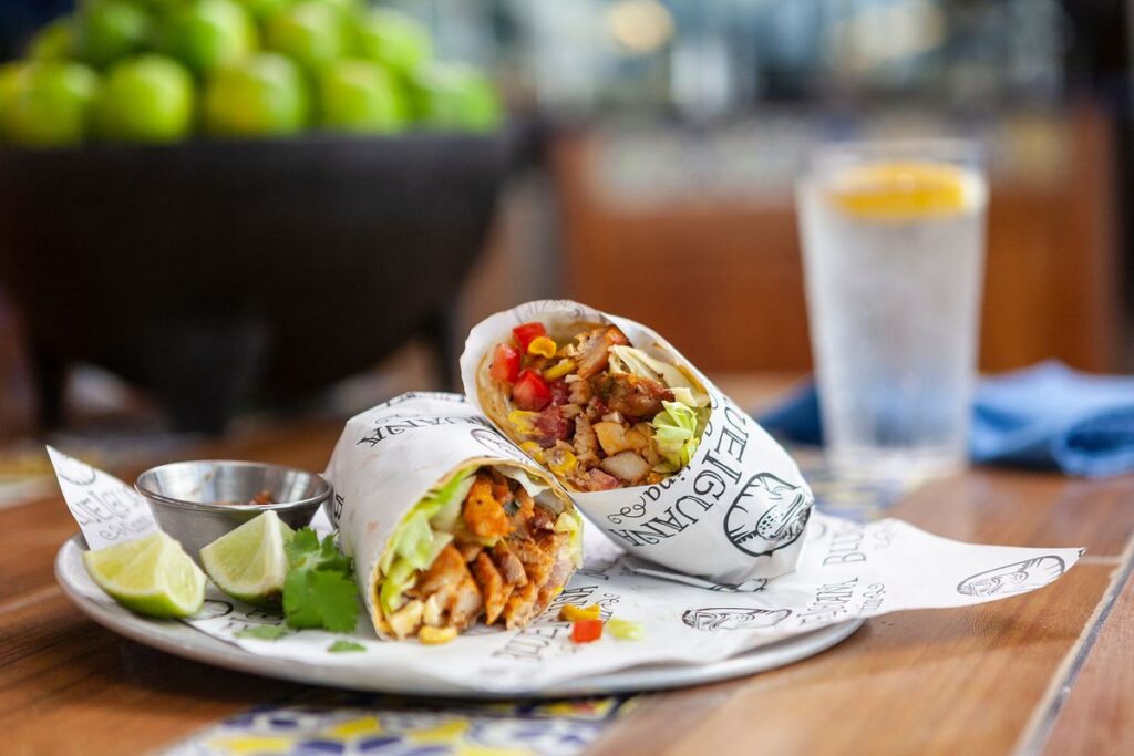A deliciously prepared burrito from BlueIguana Cantina on Carnival Spirit, accompanied by a refreshing glass of water with a lemon slice, served on a decorative plate for a flavorful meal experience.