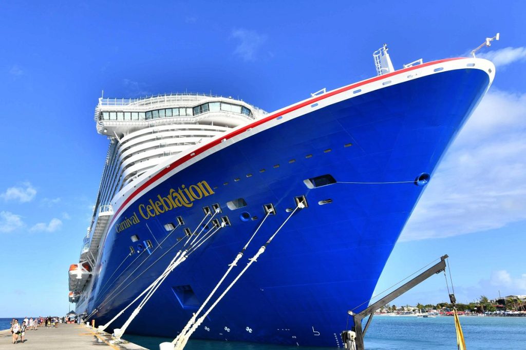 The majestic Carnival Celebration cruise ship docked at Grand Turk, towering against a brilliant blue sky.