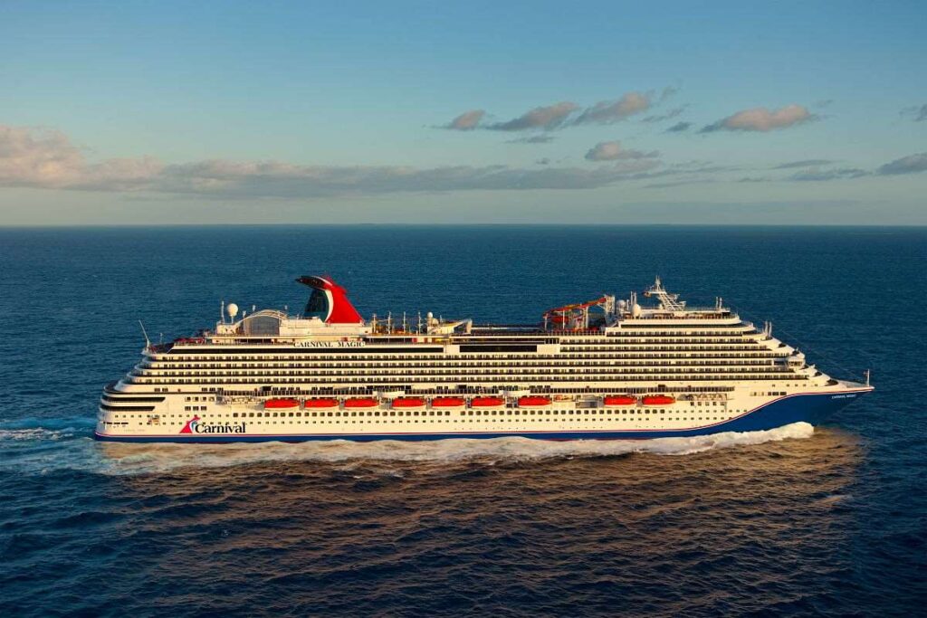 The Carnival Magic cruise ship is captured in a serene maritime setting as the golden sunlight bathes its white superstructure and red funnel, cruising on the glistening blue ocean.
