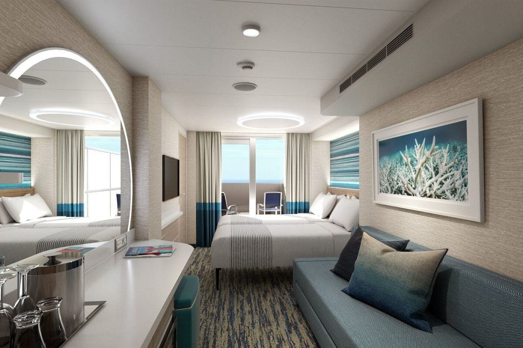 Spacious and modern Carnival cruise ship extended balcony stateroom featuring two twin beds, a cozy sitting area, a sleek flat-screen TV, and a large picture window leading to the balcony with ocean views.