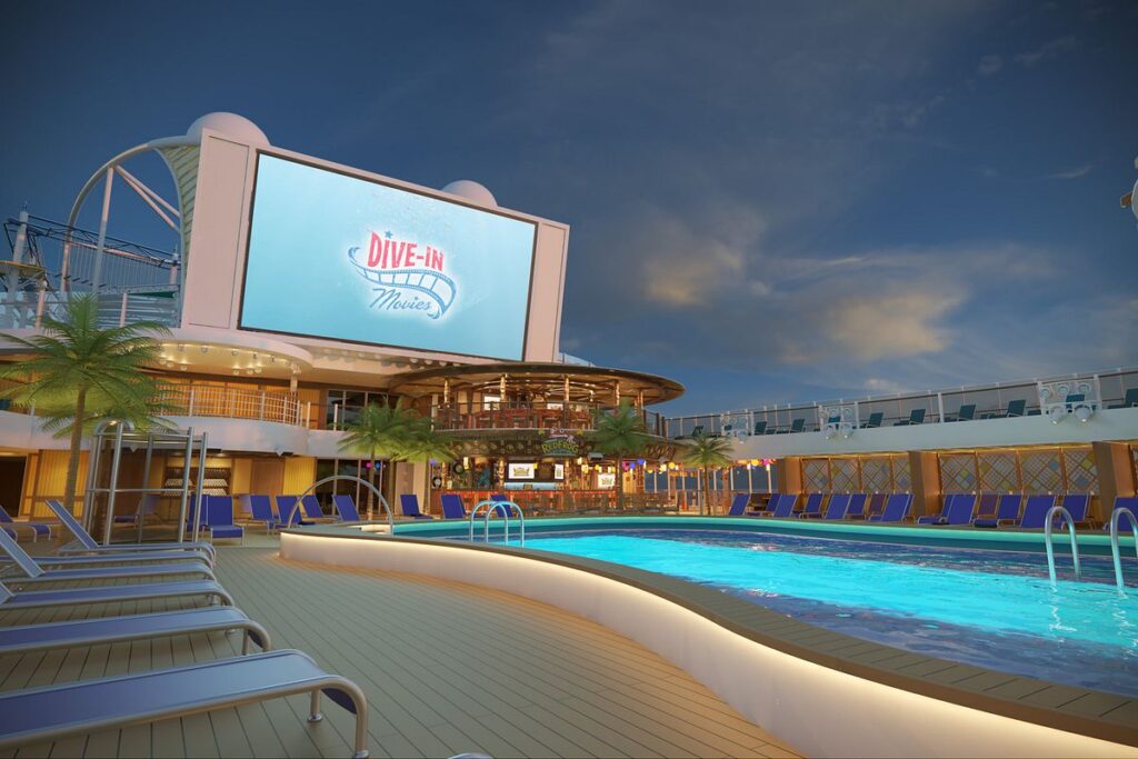 Twilight view of the Seaside Theater on Mardi Gras, featuring a large outdoor movie screen above the pool deck with cozy loungers, creating a perfect setting for 'Dive-In Movies' under the stars.