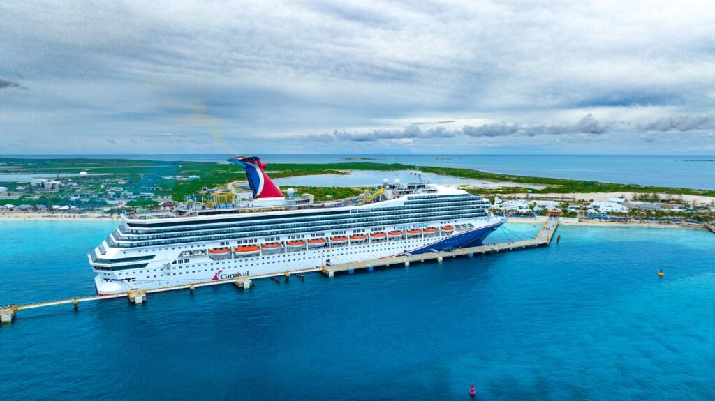The Carnival Sunrise cruise ship docked at Grand Turk, with the island's stunning turquoise waters and lush landscapes in the background, embodying tropical travel and leisure.