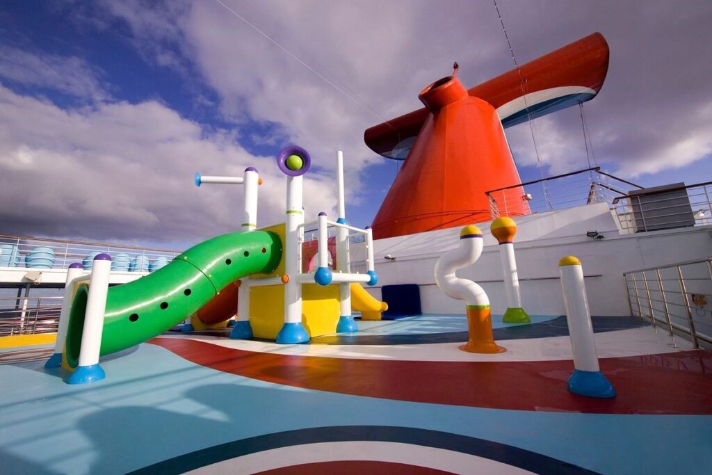 Colorful Splash Park with slides and water features on the deck of Carnival Splendor cruise ship, under a blue sky with scattered clouds.