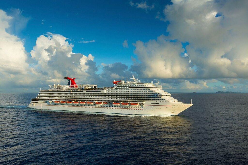 The majestic Carnival Vista cruise ship embarks on a voyage, captured with its signature red funnel against a backdrop of dramatic clouds and a glistening ocean, with distant islands on the horizon.