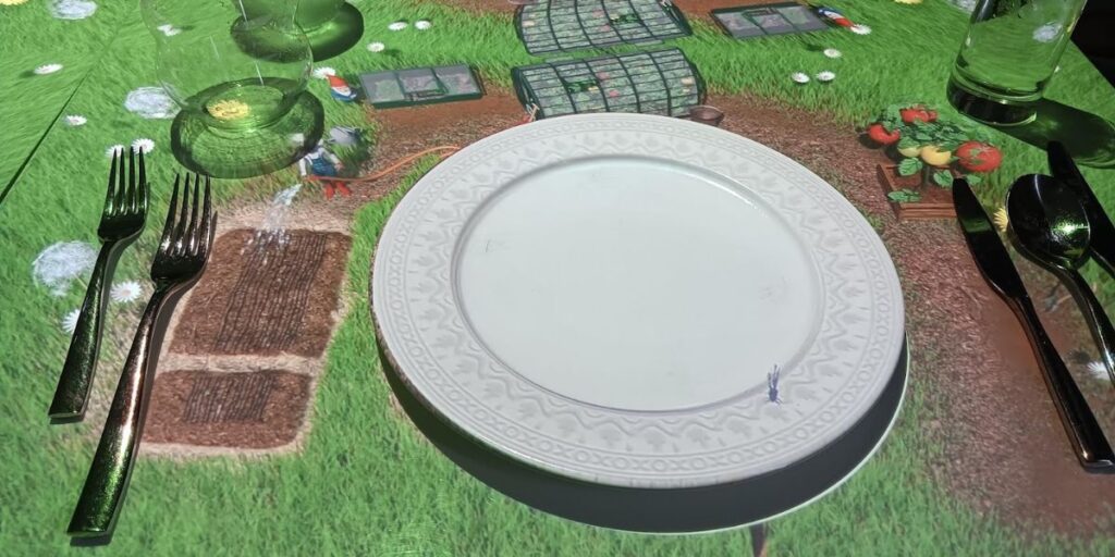 A dining table on the Celebrity Apex cruise ship featuring an interactive digital projection of a garden scene, complete with animated vegetables and greenery. The table is set with white plates, glasses, and cutlery, creating an immersive and playful dining experience for guests.