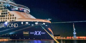 Celebrity Beyond docked at night with illuminated decks and hull, creating a dramatic, moody atmosphere.