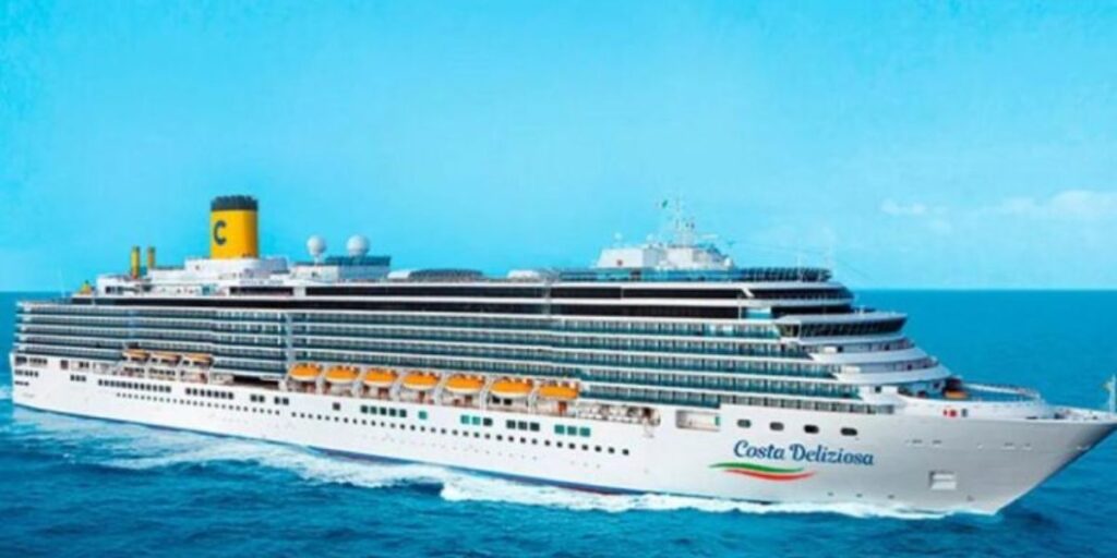 The Costa Deliziosa cruise liner advances across the deep blue sea, its white structure dotted with rows of balconies and the iconic yellow funnel marked with a 'C', evoking the essence of luxury sea travel.