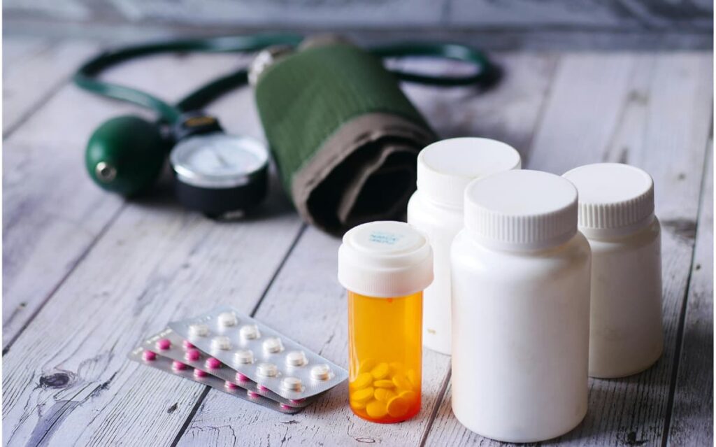 Assortment of medication bottles and a blood pressure cuff, highlighting the importance of properly declaring and transporting required medications on cruises.