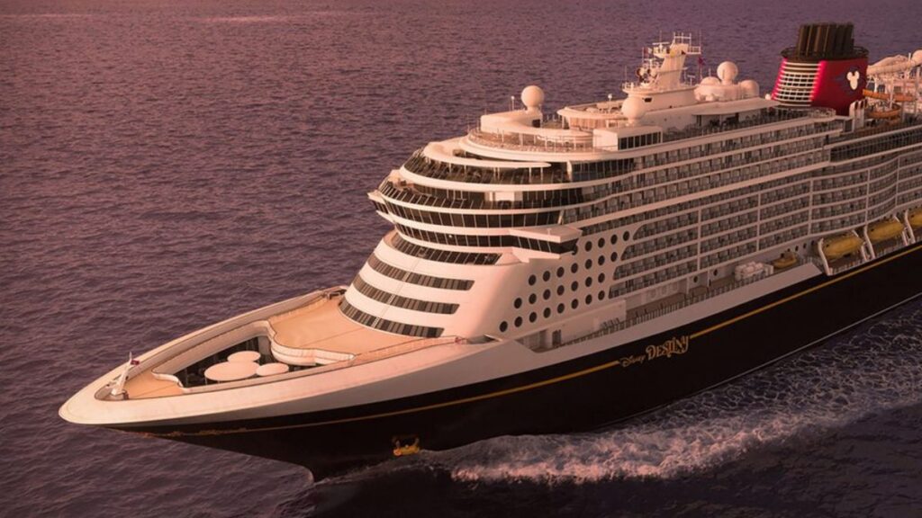 The Disney Destiny cruise ship sails through calm waters at sunset, its elegant black, white, and gold hull gleaming in the soft evening light. The ship's signature red funnels feature the classic Mickey Mouse logo, embodying Disney Cruise Line’s signature magical design. With luxurious decks and a grand bow, the vessel exudes both sophistication and family-friendly adventure on the high seas.